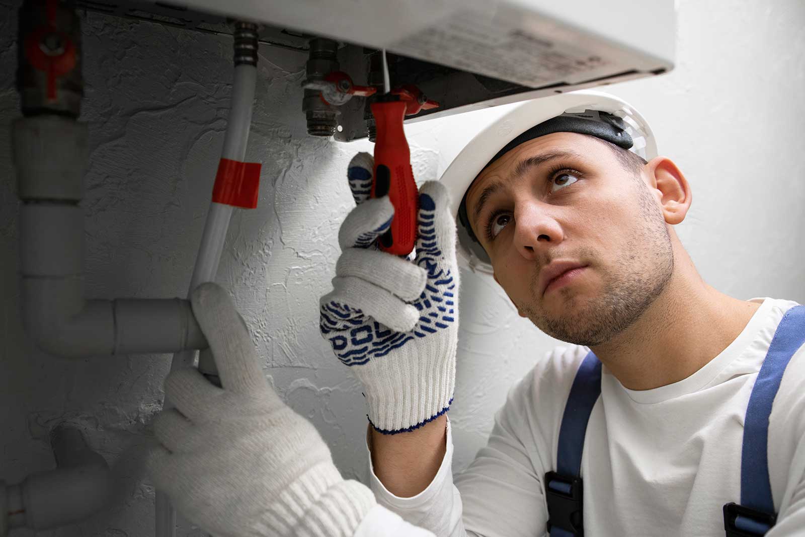 Professional HVAC technician inspecting and repairing a residential furnace system using tools.