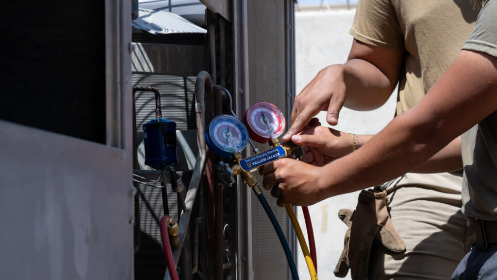 HVAC technician checking refrigerant pressure during AC efficiency troubleshooting