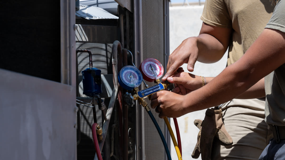 HVAC technician checking refrigerant pressure while troubleshooting an AC system freezing up in Florida heat